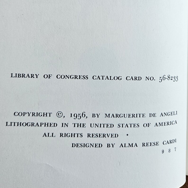 May include: A black and white image of a book's copyright page. The text reads "Copyright &copy;, 1956, by Marguerite de Angeli. Lithographed in the United States of America. All rights reserved. Designed by Alma Reese Cardi."
