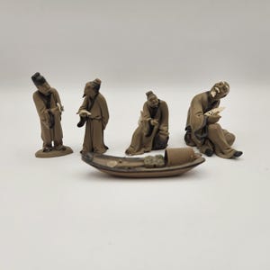 Grupp med fyra små lermän i vintagestil och en miniatyr-sampan