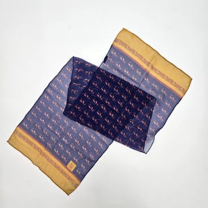 May include: A rectangular scarf featuring a deep navy blue base with a repeating pattern of small, light-colored leaf motifs. The scarf has wide, solid mustard yellow borders on both ends, accented by a thin, intricate decorative trim.