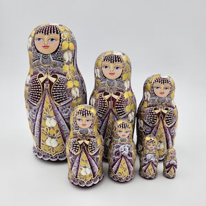 May include: A set of seven nesting dolls, also known as Russian nesting dolls, with a burgundy base and gold and white painted details. The dolls are all wearing traditional Russian clothing and have painted faces. The largest doll is about 10 inches tall and the smallest doll is about 1 inch tall.