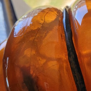 May include: Close-up of a clear amber glass bottle with a black rubber seal. The bottle has a textured surface and the text "CH" is visible on the side.