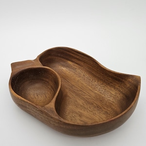 May include: A wooden serving dish with two sections. The larger section is oval shaped and the smaller section is a heart shape. The dish is made of dark brown wood.