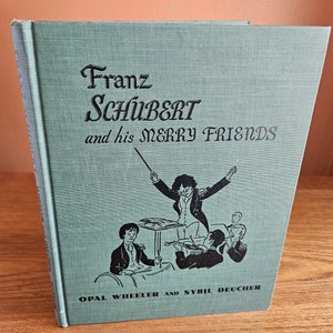 May include: A green book with the title "Franz Schubert and his Merry Friends" in black text. The cover features a black and white illustration of a conductor leading a group of musicians.