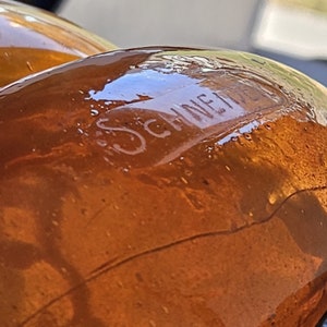 May include: Close-up of a brown glass bottle with the word "SCHNEIDER" embossed on the side.