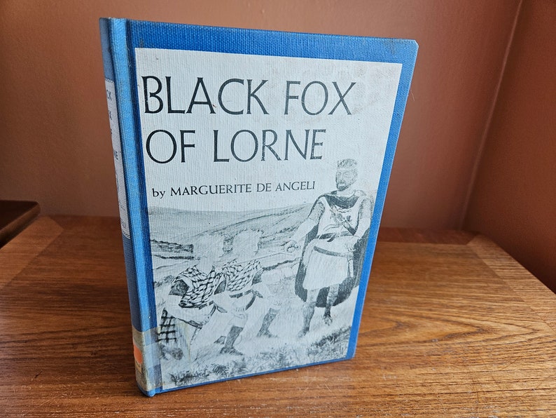 May include: A blue book cover with the title "Black Fox of Lorne" by Marguerite de Angeli. The cover features a black and white illustration of a man in a kilt and two other figures.
