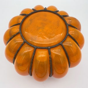 May include: Orange glass pumpkin-shaped bowl with a black metal wire frame.