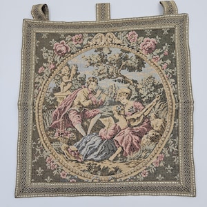 May include: Tapestry wall hanging featuring a romantic scene within a circular frame. The image shows figures in period attire, including a musician and a couple, set amongst flowers and foliage. The border is dark green with a decorative pattern.