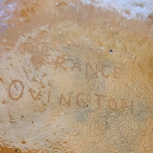 May include: Close-up of a brown ceramic object with the words "FRANCE" and "OWINGTOH" written on it.
