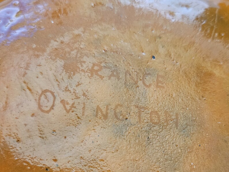 May include: Close-up of a brown ceramic object with the words "FRANCE" and "OWINGTOH" written on it.