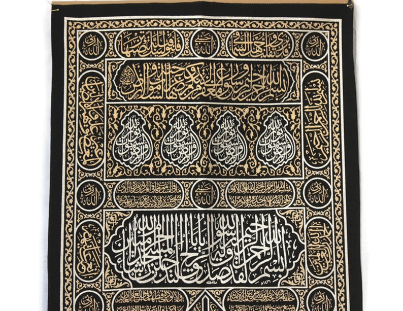 May include: Black fabric with gold and silver embroidery depicting Islamic calligraphy. The fabric features intricate patterns and designs.