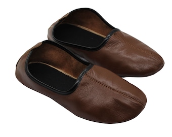 May include: A pair of brown leather slippers with black trim. The slippers are made of soft leather and have a comfortable fit.