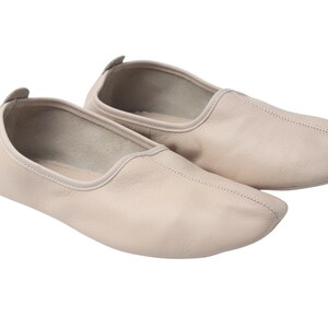 Pu&ograve; includere: Un paio di scarpette da ballo in pelle beige. Le scarpe hanno una punta arrotondata e un profilo basso, con una piccola linguetta sul tallone. Le cuciture sono visibili lungo le cuciture. Queste scarpette da ballo sono progettate per il comfort e la flessibilit&agrave;.