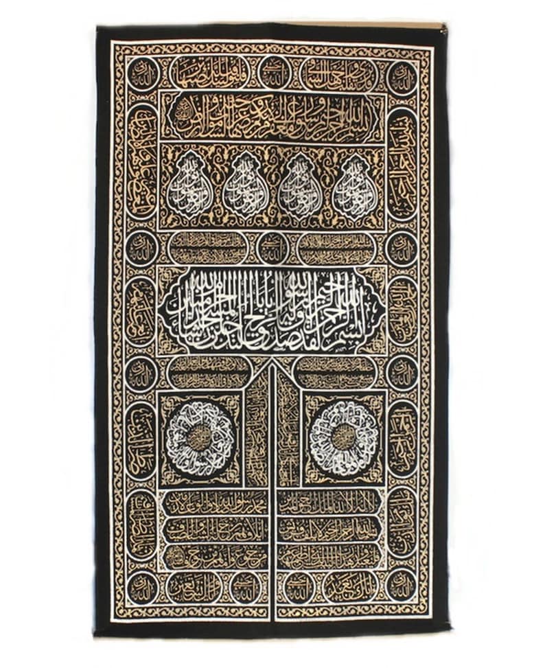 May include: Black fabric wall hanging with gold and white embroidery depicting the Kaaba, a cube-shaped building in Mecca, Saudi Arabia. The embroidery features intricate Arabic calligraphy.