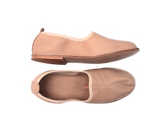 Puede incluir: Dos mocasines de cuero marrón claro se muestran sobre un fondo blanco. Los zapatos tienen punta redonda y tacón bajo. El zapato superior se ve de lado, el inferior desde arriba.
