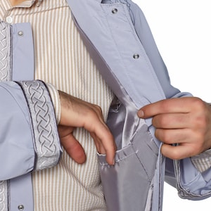 May include: A light grey jacket with a zip fastening and a decorative braid detail on the sleeves and collar. The jacket has an inside pocket.