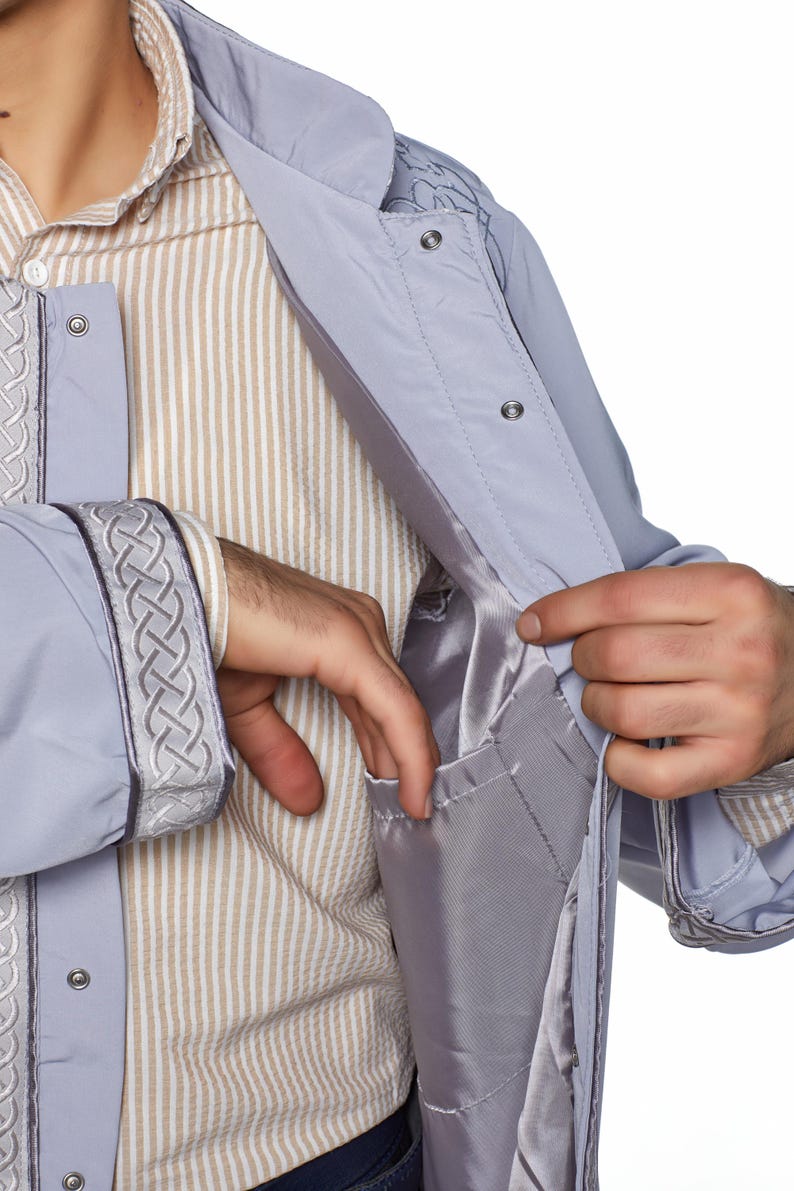 May include: A light grey jacket with a zip fastening and a decorative braid detail on the sleeves and collar. The jacket has an inside pocket.