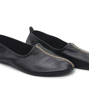 Puede incluir: Par de zapatos negros de cuero con detalles de costuras doradas.