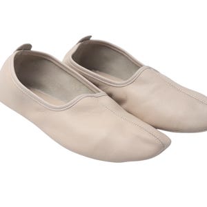 Pu&ograve; includere: Un paio di ballerine in pelle beige chiaro. Le scarpe hanno una punta arrotondata e un piccolo tacco arrotondato. Le cuciture sono visibili lungo le cuciture. Le scarpe sono progettate per il comfort e la flessibilit&agrave;.