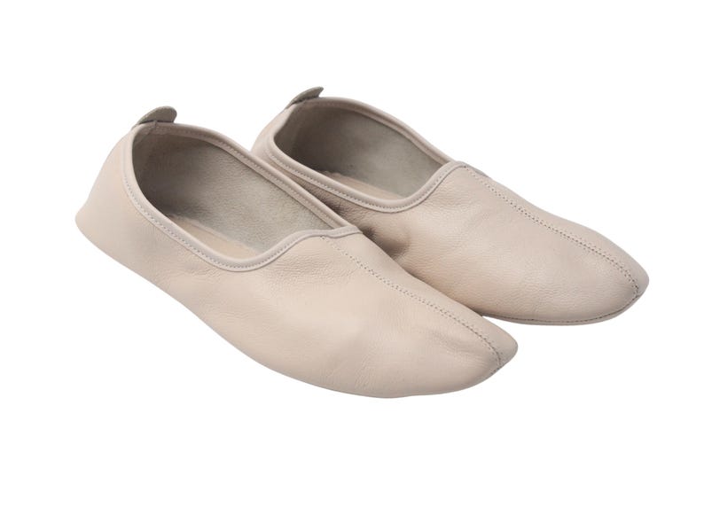 Pu&ograve; includere: Un paio di ballerine in pelle beige chiaro. Le scarpe hanno una punta arrotondata e un piccolo tacco arrotondato. Le cuciture sono visibili lungo le cuciture. Le scarpe sono progettate per il comfort e la flessibilit&agrave;.