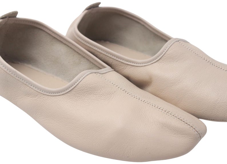 Pu&ograve; includere: Un paio di ballerine in pelle beige chiaro. Le scarpe hanno la punta arrotondata e una cucitura cucita al centro. I bordi sono rifiniti con un colore beige pi&ugrave; chiaro. Le scarpe sono progettate per il comfort e la flessibilit&agrave;.
