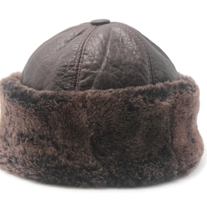 May include: A brown leather hat with a fur trim. The hat has a rounded crown and a button on top. The fur trim is a darker shade of brown. This hat is designed to keep the wearer warm.