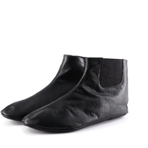Puede incluir: Un par de botines de cuero negro. Una bota est&aacute; delante de la otra, mostrando el perfil lateral. Las botas tienen punta redondeada y paneles laterales el&aacute;sticos. Las botas son de cuero suave y texturizado.