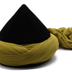 May include: A black velvet cone-shaped hat with a long, mustard yellow fabric wrap.
