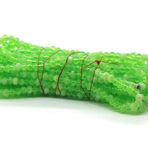 May include: A bundle of green glass beads, tied together with brown string. The beads are translucent and have a slight shimmer.