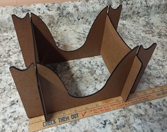 May include: A brown cardboard box with a unique curved design. The box is made of four pieces that fit together to create a unique shape. The box is approximately 33 cm long and 15 cm wide.