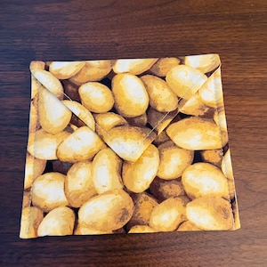 May include: A brown and yellow fabric pot holder with a pattern of potatoes.