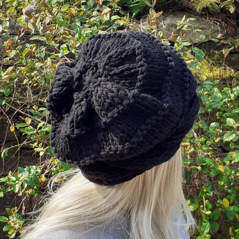 May include: A black knitted beanie with a textured pattern. The beanie is worn on a person's head.