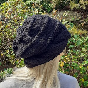 May include: A black knitted beanie with a cable knit pattern. The beanie is slouchy and has a relaxed fit.