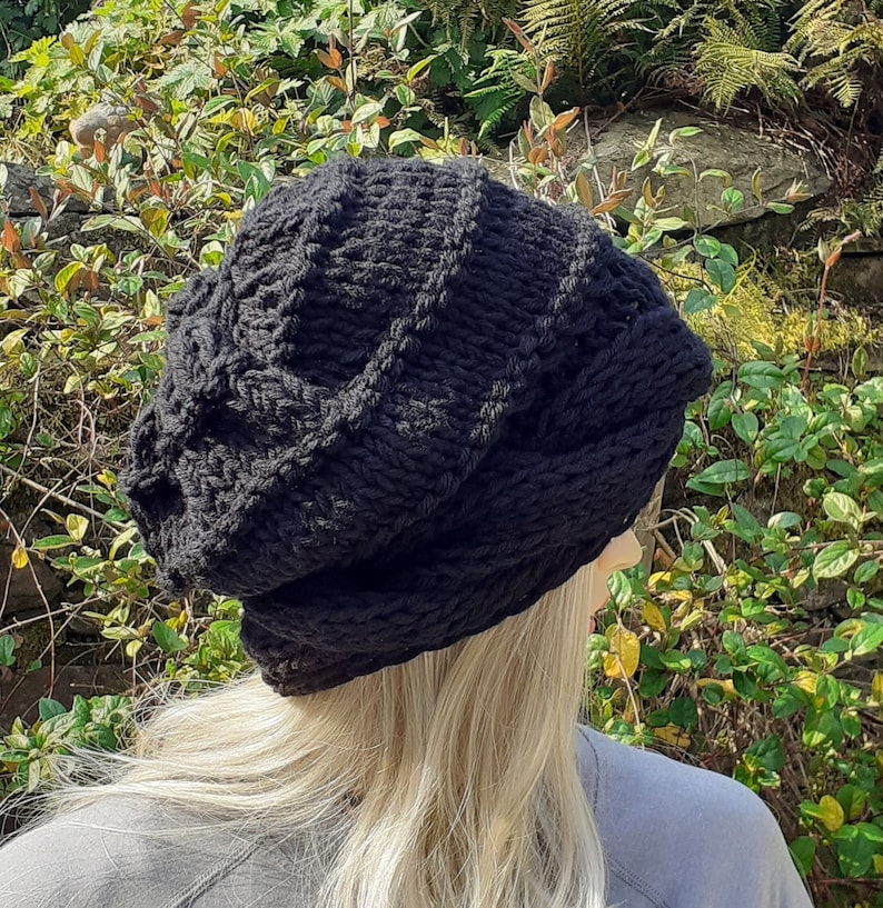 May include: A black knitted beanie with a cable knit pattern. The beanie is slouchy and has a relaxed fit.