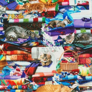 May include: A colourful fabric collage featuring a sewing machine, spools of thread, scissors, and several cats. The cats are in various poses, including sleeping, sitting, and looking at the viewer. The fabric is a mix of patterns and colours, including red, blue, green, yellow, and purple.