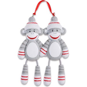 May include: Two grey sock monkey ornaments with red and white stripes, wearing white knitted hats with red pom-poms. The monkeys are holding hands and have blank white faces.
