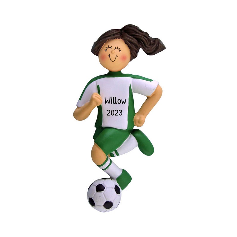 May include: Green and white soccer player ornament with brown hair, smiling, kicking a soccer ball. The ornament has the name "Willow" and the year "2023" printed on the front.