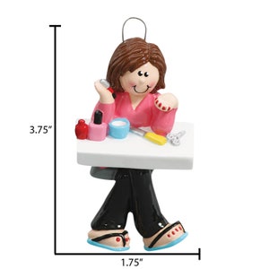 Puede incluir: Un adorno de cer&aacute;mica pintado a mano que representa a una persona sentada en una mesa con esmalte de u&ntilde;as y herramientas. El adorno mide 9,5 cm de alto y 4,5 cm de ancho.