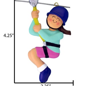 Peut inclure: Une d&eacute;coration de No&euml;l en forme de personne en train de faire de la tyrolienne, de couleur bleue et rose. La d&eacute;coration mesure 4,25 pouces de haut et 2,25 pouces de large.