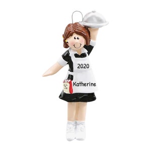 May include: A personalized Christmas ornament featuring a cartoon waitress wearing a black and white uniform, a white apron with the year 2020 printed on it, and a silver serving tray. The ornament also includes a notepad with the name "Katherine" written on it.