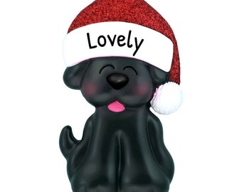 May include: Black Labrador Retriever dog Christmas ornament wearing a red Santa hat with white trim and the word "Lovely" written on the front.