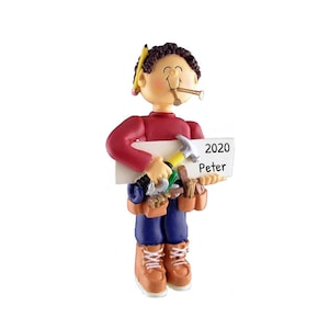 May include: A personalised Christmas bauble featuring a cartoon man with brown hair, wearing a red shirt, blue trousers, and brown boots. He is holding a sign that says "2020 Peter" and has a tool belt with a hammer, nails, and other tools.