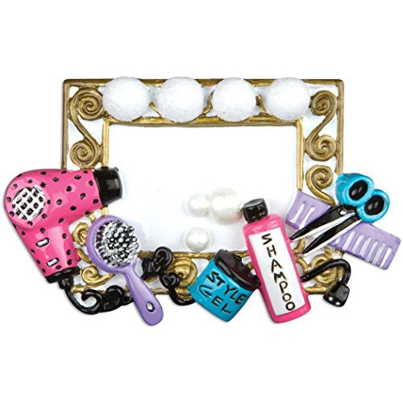 May include: A gold-colored picture frame with a white background and various hair styling tools, including a pink hair dryer, a purple brush, a blue bottle labeled "Style Gel", a pink bottle labeled "Shampoo", a pair of silver scissors, and a purple comb.