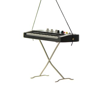 May include: Miniature black and white keyboard with a silver stand. The keyboard has white keys, black keys, and several knobs and buttons in various colors. The stand is made of silver metal and is in an X shape.