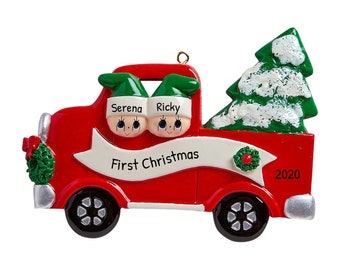 May include: Red toy truck Christmas ornament with two elves in the cab, a Christmas tree in the bed, and the text "First Christmas 2020".