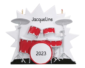May include: A white and red drum set Christmas ornament with the name Jacqueline and the year 2023.