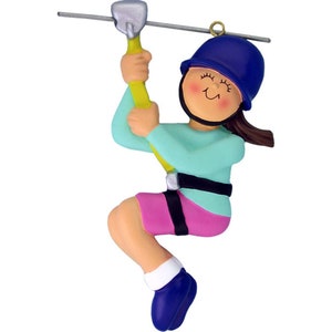 Peut inclure: Une figurine de fille en train de faire de la tyrolienne avec un casque bleu, un short rose et une chemise turquoise. Elle tient une corde jaune et porte un harnais noir.