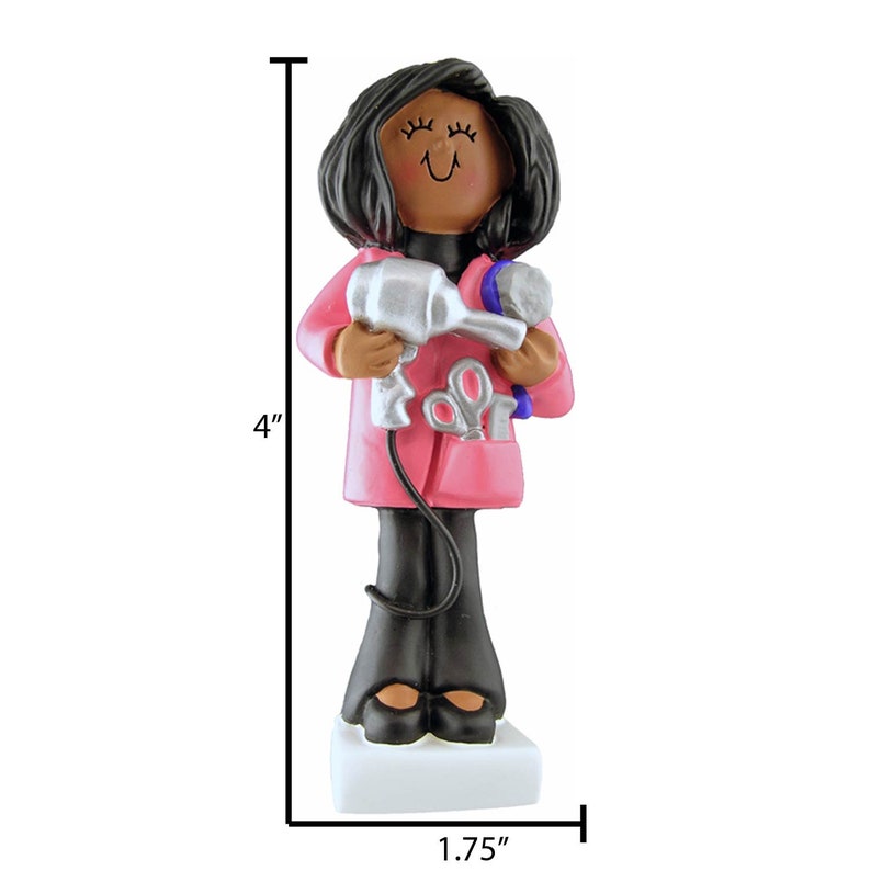 May include: A figurine of a Black woman hairstylist, 4 inches tall, wearing a pink coat and black pants. She holds a silver hairdryer and a blue hairbrush. A pair of scissors is in her pocket. The figurine is on a white base, 1.75 inches wide.