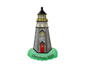 Könnte beinhalten: Ein grauer Stein-Leuchtturm-Weihnachtsbaumschmuck mit einer roten Tür und gelben Fenstern. Die Basis ist grün und trägt die Aufschrift "Christmas 2020".