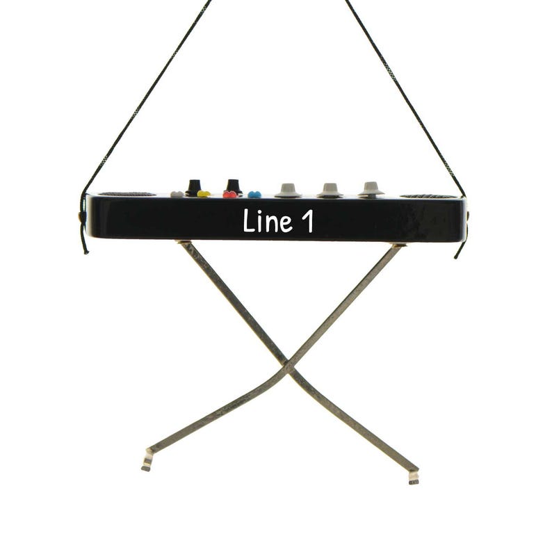 May include: A black electronic device with the text "Line 1" on the front, supported by a silver metal stand. The device has several colored buttons and knobs on top and is suspended by a black string.