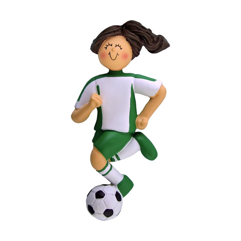 May include: A green and white soccer player ornament with brown hair and a ball at their feet.